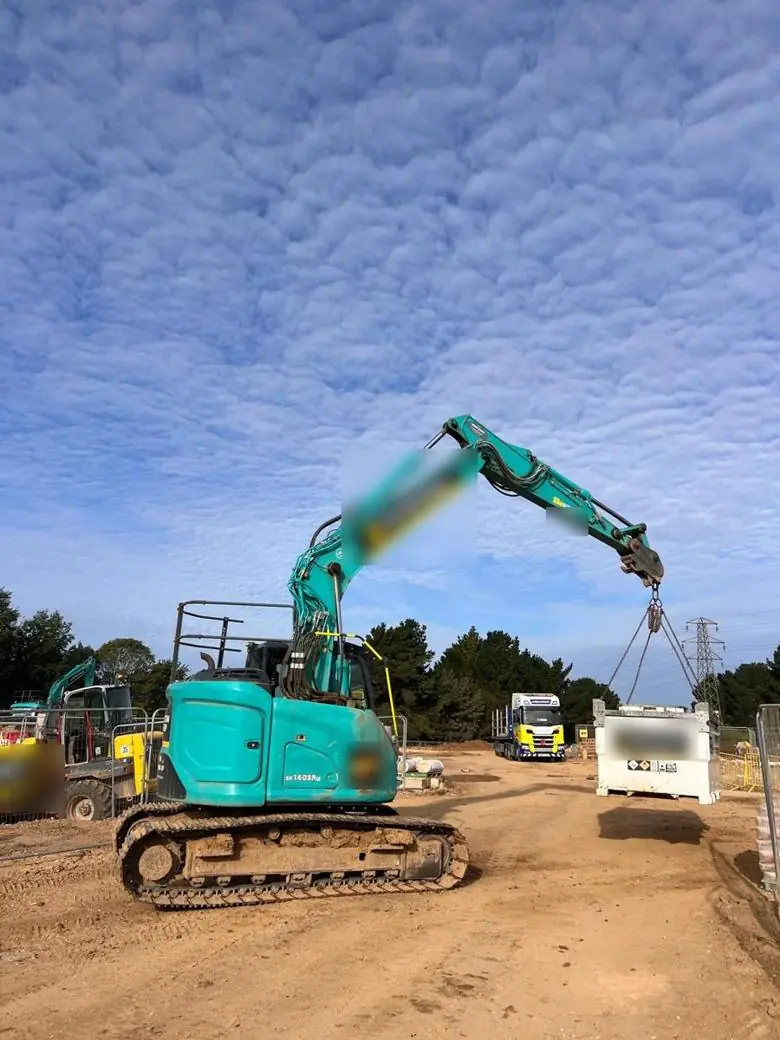 Excavator lifting a fuel cube on a four-leg chain sling